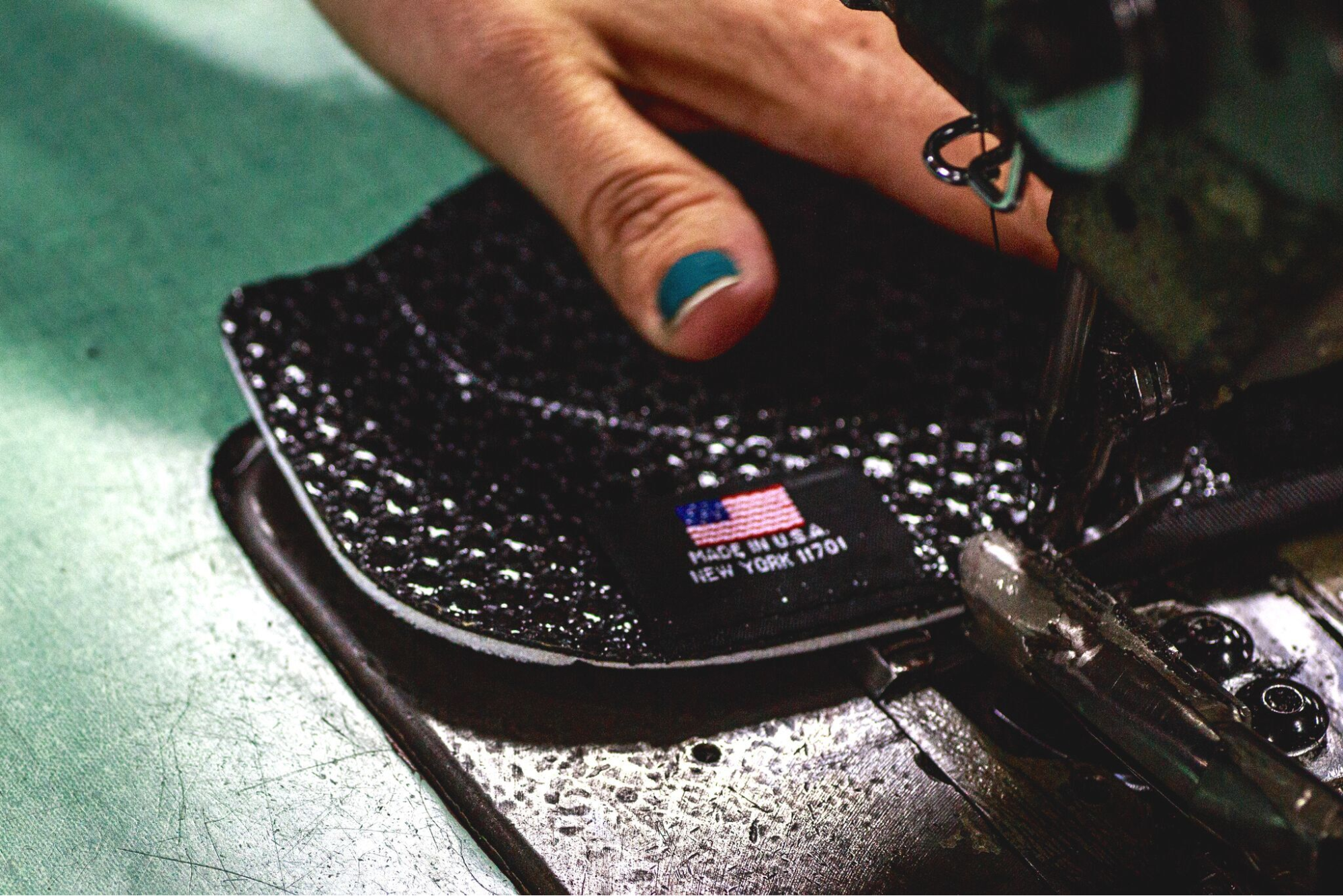 Close-up view of a person cleaning a black firearm holster with a cloth on a work surface.