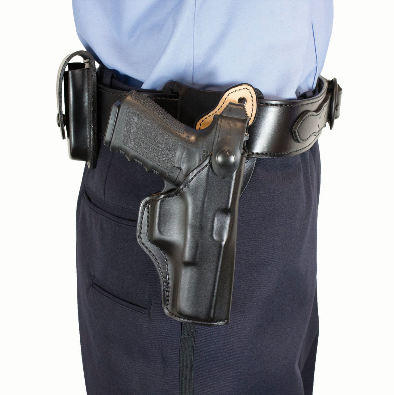 Person wearing a black leather gun belt with a handgun secured in an outside-the-waistband retention holster.