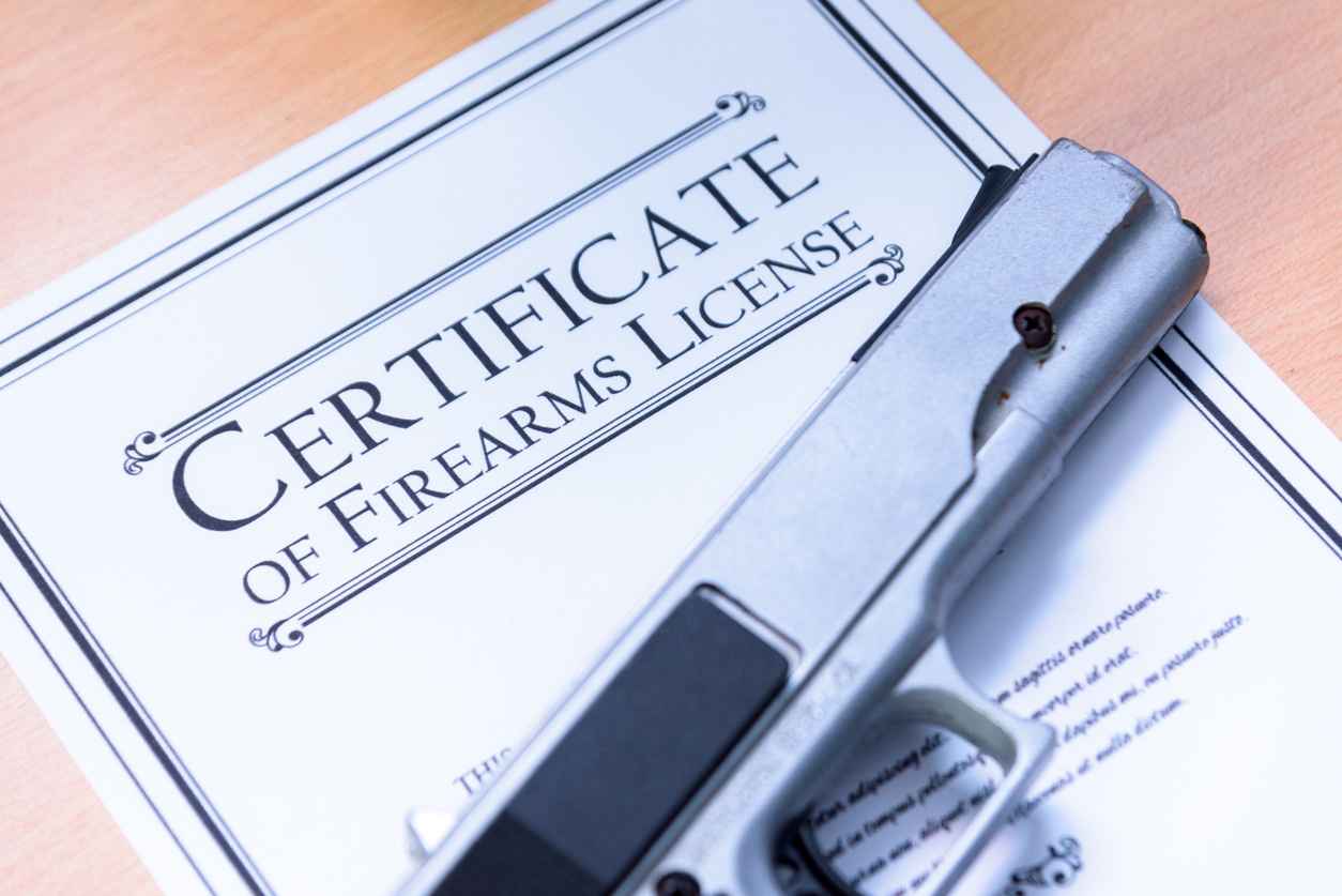 Handgun placed on top of a firearm license certificate document on a desk.